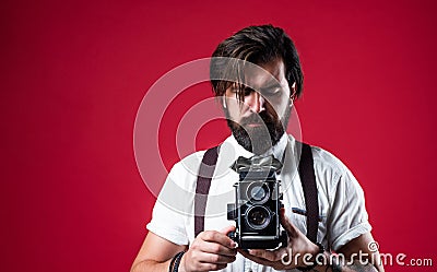 bearded man in suspenders making vintage photo. elegant businessman hold retro camera. journalist use old technology Stock Photo