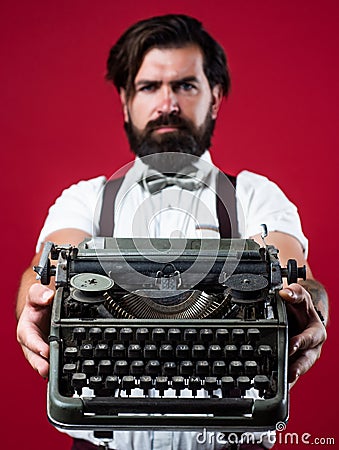 bearded man in suspenders with retro typewriter. brutal guy in bow tie. elegant male typist. handsome hipster use Stock Photo