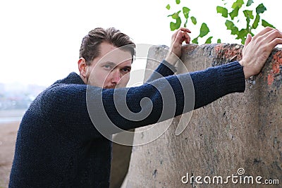 Bearded man in sweater leant on the wall Stock Photo