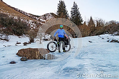 A bearded man travels in the mountains on a fat bike in winter Stock Photo