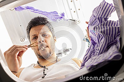 Bearded man using washing machine at home Stock Photo