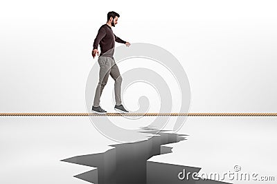 A bearded man is very concentrated when walking on a tight rope above a crack in the earth. Stock Photo