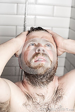 Bearded man washing her hair in the shower under running water. Stock Photo