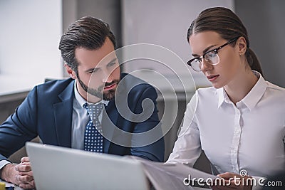 Bearded man and woman in glasses looking at documents Stock Photo