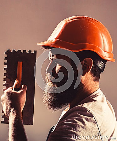 Bearded man worker, beard, building helmet, hard hat. Mason plastering concrete to build. Plastering tools. Tool, trowel Stock Photo