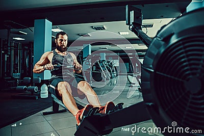 Muscular fit man using rowing machine at gym Stock Photo