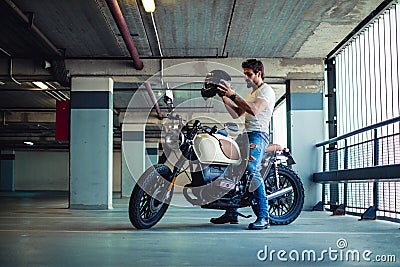 Man putting on motorcycle helmet in a garage Stock Photo