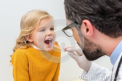 bearded pediatrist checking throat of adorable Stock Photo