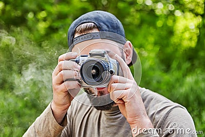 Bearded photographer in baseball cap makes a photo Stock Photo