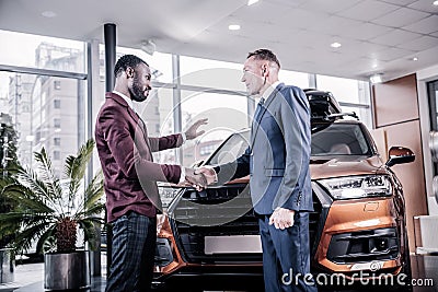Bearded sales manager wearing squared trousers shaking hand of client Stock Photo
