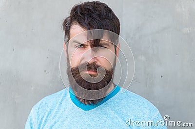 Bearded and shaggy. Bearded man with stylish haircut on grey wall. Unshaven caucasian guy wearing thick mustache and Stock Photo