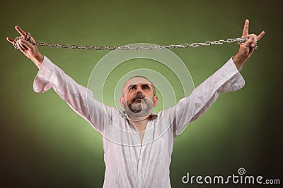 A bearded short-haired elderly man with chain in his hands shows a rockers goat Stock Photo
