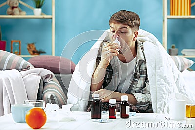 Bearded sick man with flue sitting on sofa at home. Illness, influenza, pain concept. Relaxation at Home. Healthcare Stock Photo