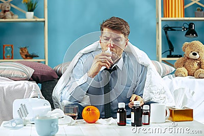 Bearded sick man with flue sitting on sofa at home. Illness, influenza, pain concept. Relaxation at Home. Healthcare Stock Photo