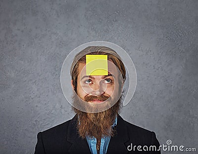 Bearded smiling business man looking up to the sticker stick on his head forehead Stock Photo