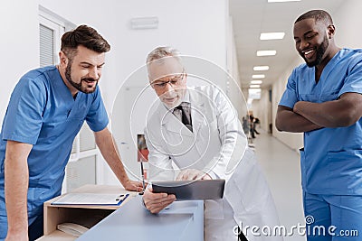 Bearded smiling practitioner enjoying conversation with colleagues at work Stock Photo