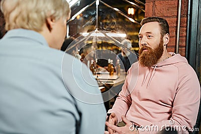 bearded tattooed men talking to middle Stock Photo