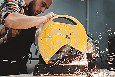 Bearded worker using electrical grinding machine in service station. Work in action. Sparks fly apart Stock Photo