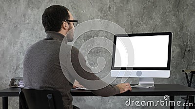 Bearded young businessman woking on computer. White Display. Stock Photo