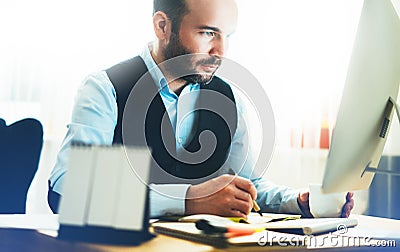 Bearded young businessman working on modern office. Consultant man thinking looking in monitor computer. Manager typing on keyboar Stock Photo