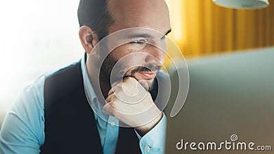 Bearded young businessman working on modern office at night. Consultant man thinking looking in monitor computer. Manager typing o Stock Photo