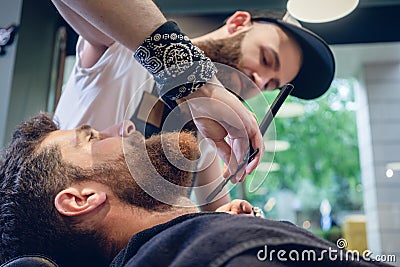 Bearded young man ready for shaving in the hair salon of a skilled barber Stock Photo