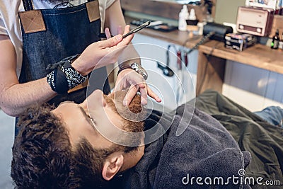 Bearded young man ready for shaving in the hair salon of a skilled barber Stock Photo