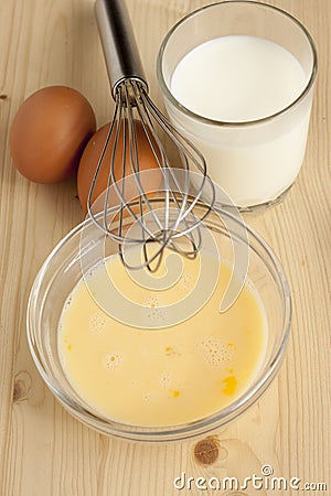 Beat eggs with milk in a glass bowl Stock Photo