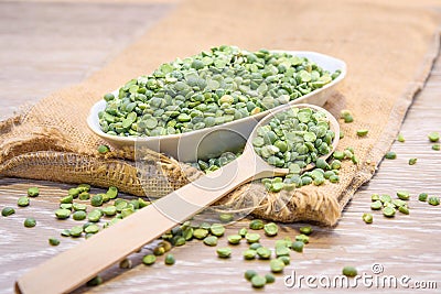Beat green peas dry in a bowl with a wooden spoon on a wooden background. Stock Photo