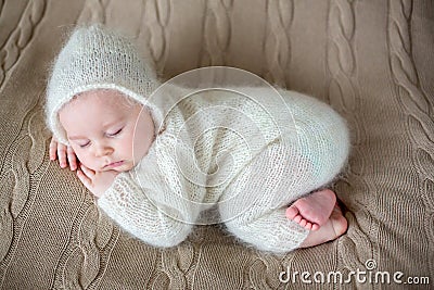 Beatiful baby boy in white knitted cloths and hat, sleeping Stock Photo