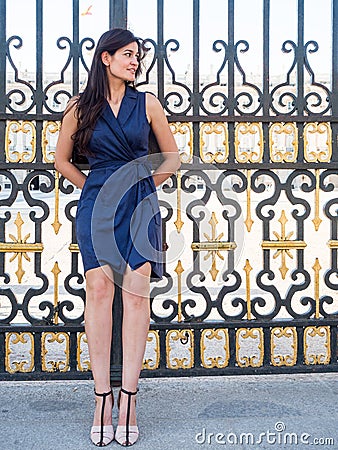 Beatiful brunette woman leaning back on a palace's gate Stock Photo