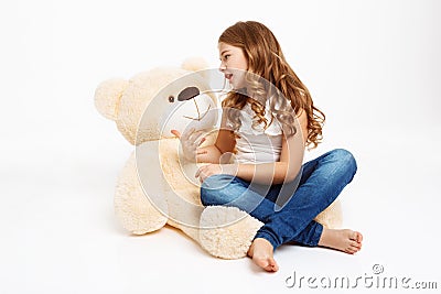 Beatiful girl sitting on floor with toy bear, telling story. Stock Photo