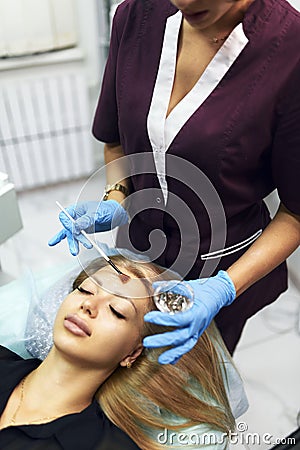 Beautician applies moisturizing cosmetic gel to the girl& x27;s face with a brush. Cosmetic rejuvenation procedure. Stock Photo