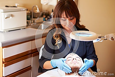 Beautician Applying Cream To Male Client In Clinic Stock Photo