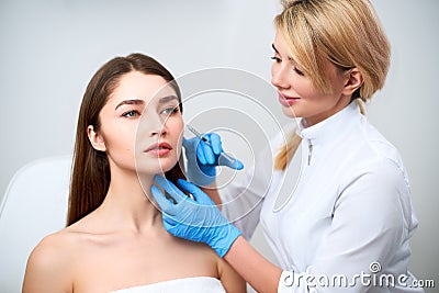 Beautician doctor with botulinum toxin syringe making injection to to remove crow`s feet. Cheek volume enhance Stock Photo