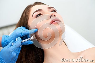 Beautician doctor with filler syringe making injection to jowls. Masseter lines reduction and face contouring therapy Stock Photo