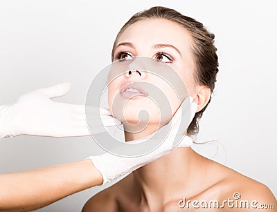 Beautician hand`s examining beautiful young female face. Stock Photo