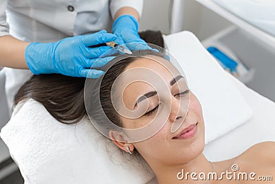 Beautician injections for healthy hair growth. Mesotherapy of the scalp. A young girl is undergoing a course of spa treatments in Stock Photo