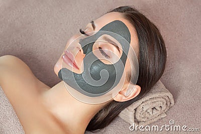 Beautician makes a black clay mask to rejuvenate the skin to beautiful woman.Cosmetology concept and treatment of problem skin Stock Photo