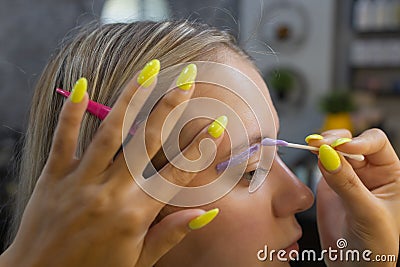 Beautician making depilation with wax strip young woman's eyebrows in spa center. Attractive woman getting facial care Stock Photo