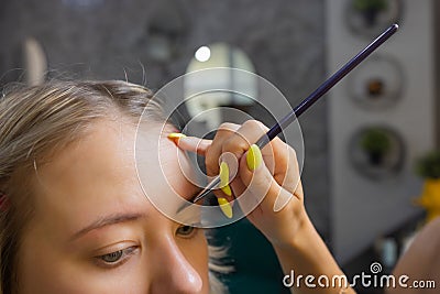 Beautician making depilation with wax strip young woman& x27;s eyebrows in spa center. Attractive woman getting facial care Stock Photo