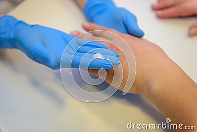 Beautician or manicurist in special medical gloves causes the cream on the woman`s hand at the table in the Spa, close-up Stock Photo