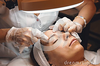 Beautician presses acne on face of young girl patient, skin cleansing, cosmetologist procedure Stock Photo