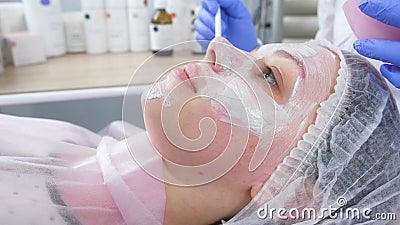 Beautician stawia białą maskę na kobiety twarzy z muśnięciem Ręki cosmetologist w błękitnych gumowych rękawiczkach facial zbiory Beautician stawia białą maskę na kobiety twarzy z muśnięciem Ręki cosmetologist w błękitnych gumowych rękawiczkach facial zbiory