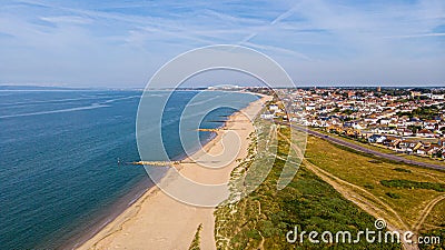 A beautiful aerial seaside view with sandy beach, crystal blue water, groynes breakwaters and green vegetation dunes along a Stock Photo