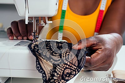 Beautiful african american tailor woman sewing laces sexy lingerie in showroom Stock Photo