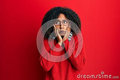 Beautiful african american woman with afro hair wearing sweater and glasses tired hands covering face, depression and sadness, Stock Photo