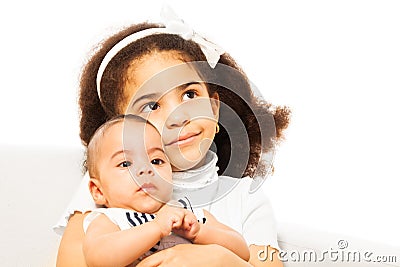 Beautiful African girl holds sister baby in arms Stock Photo