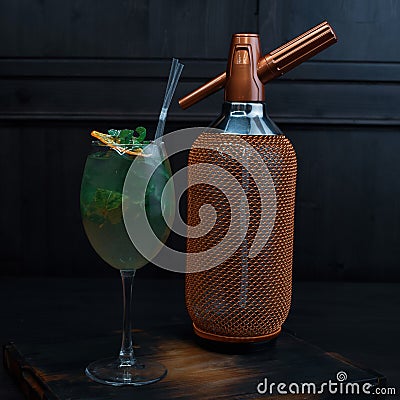 Beautiful alcoholic cocktail in an elegant glass with the addition of tequila and fresh mint leaves stands on a vintage table Stock Photo