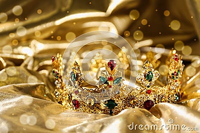 Beautiful ancient crown on golden fabric, closeup. Fantasy item Stock Photo